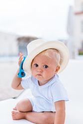 Blond baby with hat on the beach