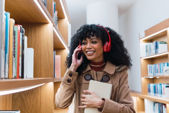 Positive Black female speaking on smartphone in library