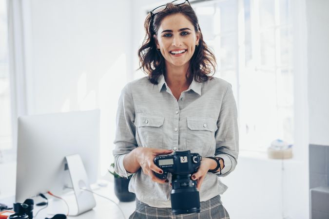 Portrait of photographer with her digital camera in her home office