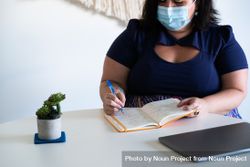 Woman in face mask writing in notebook 5kQlob