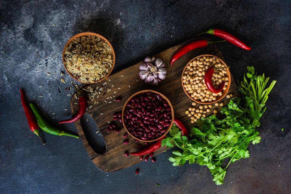Bowls of different dried beans & rice on cutting board