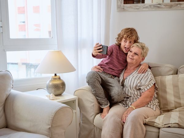 Red hair curly boy taking selfie with opened mouth with granny