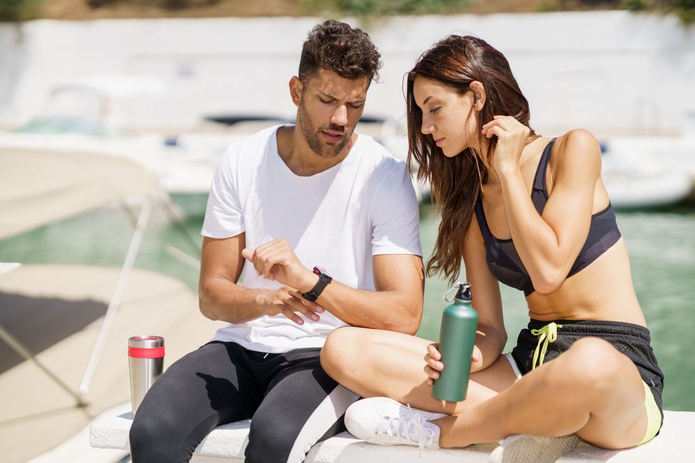 Active male and female talking together on pier after exercising