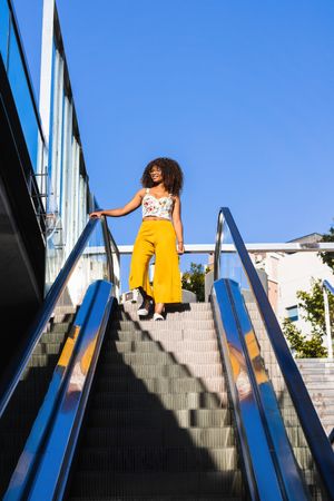 Stylish Black woman on moving stairs