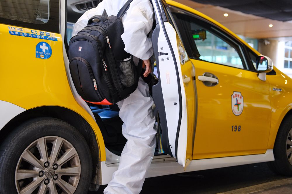Back view of person with backpack getting in a taxi car