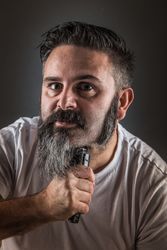 Barber shaving beard and looking at camera