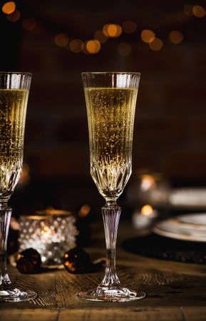 Two crystal flutes full of champagne on wooden table