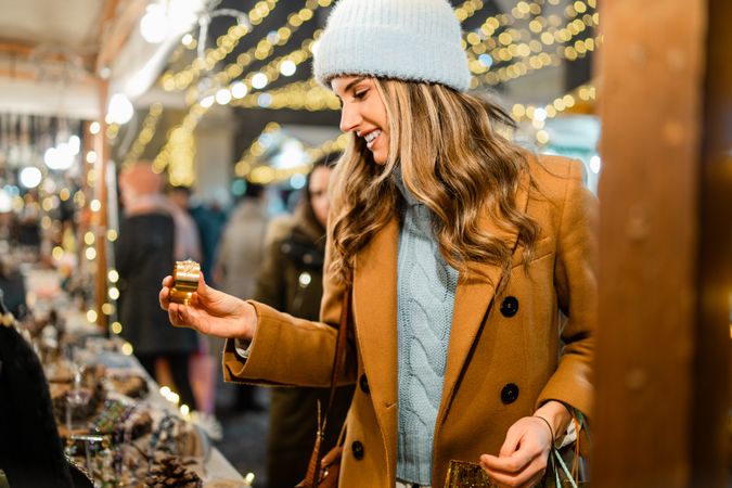 Happy young woman choosing a small gift at a Christmas market at night.