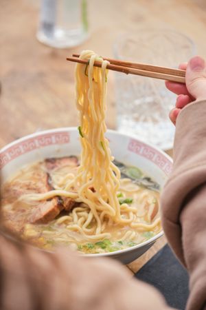 Crop woman enjoying delicious ramen soup in cafe