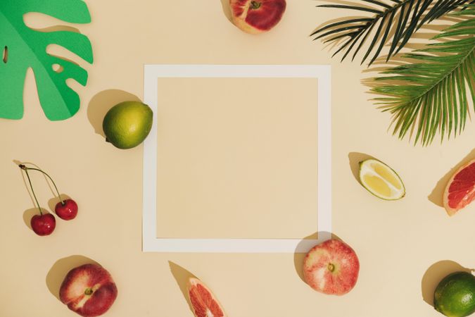 Minimal sunlit fruit and leaves composition with sand color background and sharp shadows
