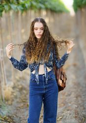 A Trendy Young Woman Dressed in a Stylish Outfit Joyfully Enjoys Nature Surrounded by a Vineyard