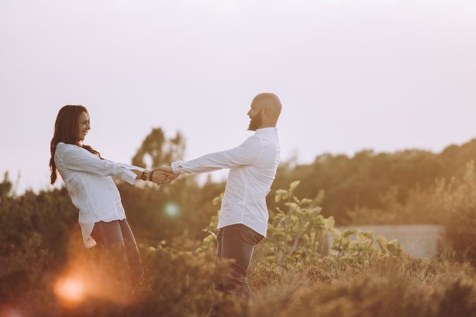 Romantic couple holding hands while standing at rural field