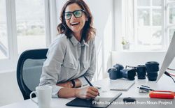 Cheerful female photographer working at her office desk 42gXdb