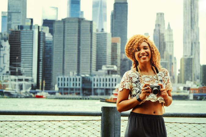 Happy Black woman photographer ready to take photos of Manhattan skyscrapers