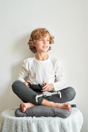 Dreamy preteen boy with drone and console of remote controller