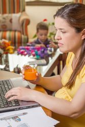 Pregnant mother working in home office with son