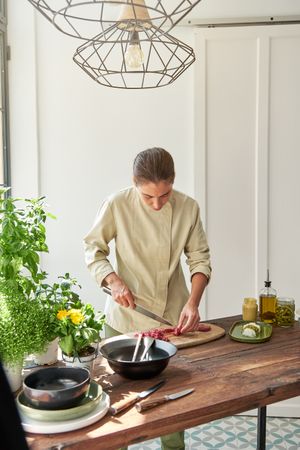 Serious woman cooking steak tartare at home