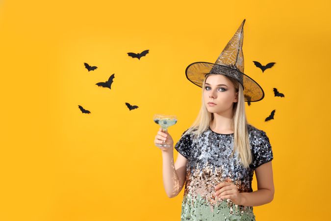 Concept of Halloween, young woman on yellow background