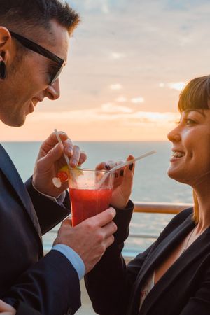 Young man and woman drinking juice from one glass