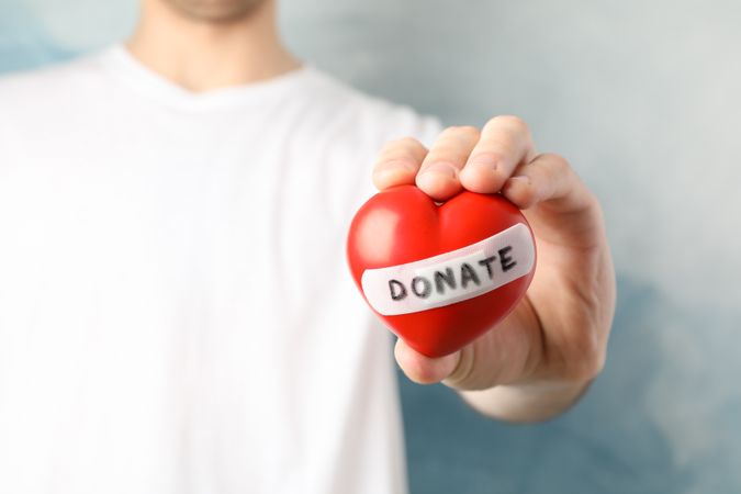 Man holds heart on blue background, close up. Health care, organ donation