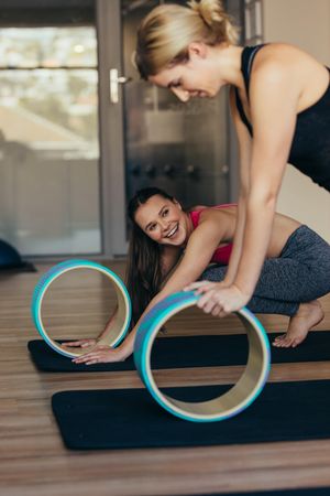 Woman in push up position resting hands on pilates wheel