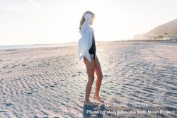 Woman touching hair on beach in oversized shirt 5qOB1b