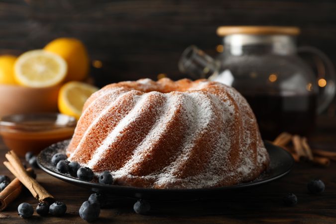 Cake with powder sugar and blueberry on wooden background, space for text
