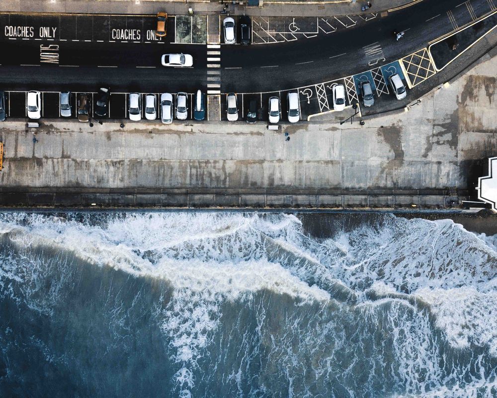 Aerial view of cars parked by seaside