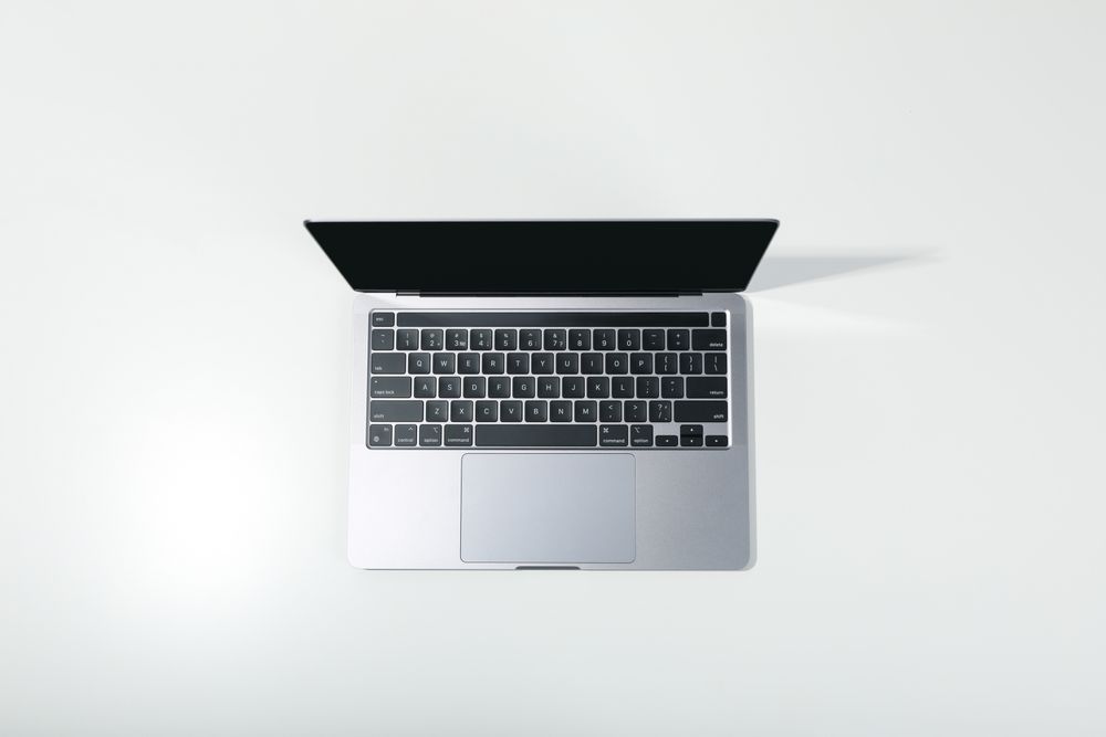 Top view of opened silver laptop and keyboard on desk