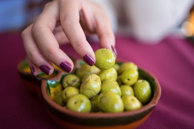 Asian woman eating olives in restaurant