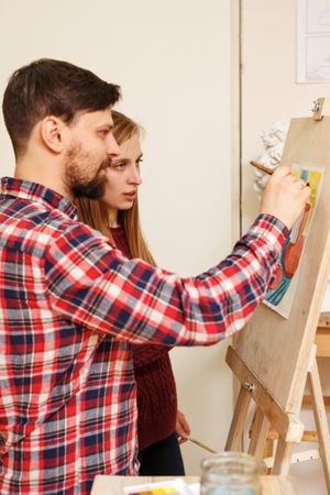 Man and woman in front of painting easel
