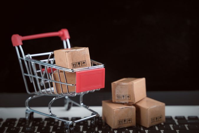 Miniature Shopping Cart on Keyboard with Cardboard Boxes Depicting Online Shopping