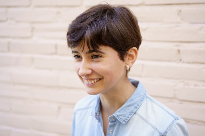 A Smiling Young Woman with Short Hair Dressed in a Casual Blue Shirt Appearing Happy and Cheerful