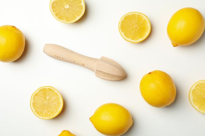 Lemons and wooden juicer on light background, top view. Ripe fruit