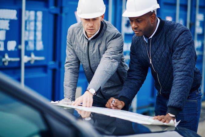 Two men in hard hats going over a blue print for a job