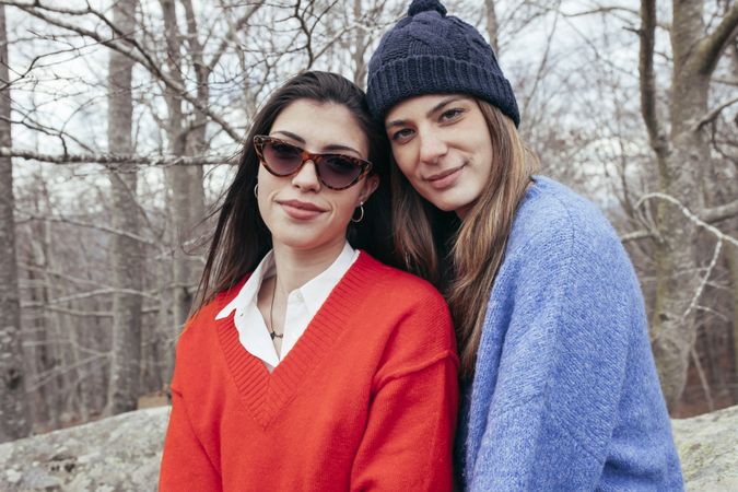 Smiling women in sweaters hugging in park