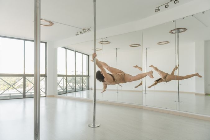 Young woman training on pole in studio