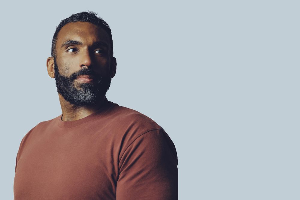 Portrait of proud Black male looking away in grey studio