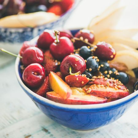 Close up of bowl of fresh fruit with cherries, peaches, blueberry, square crop