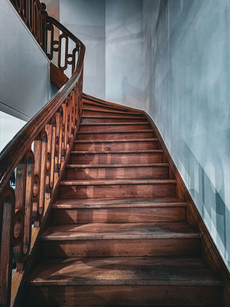 A wooden winding staircase in a stark white interior