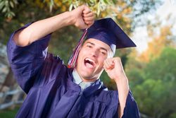 Smiling Male Graduate in Cap and Gown Outside.
