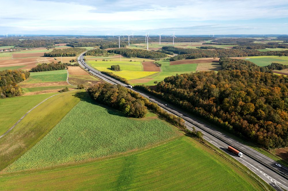 Aerial view with a two-lane highway and wind turbines in an autumn set