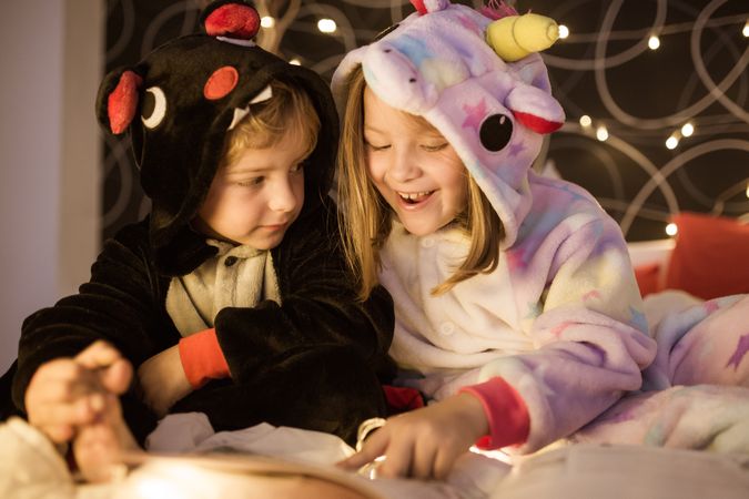 Kids reading Christmas fairy tales in bed