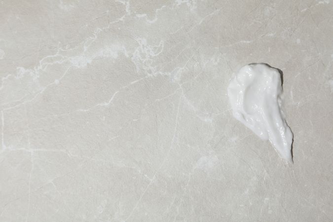 Cream drop on gray background, space for text