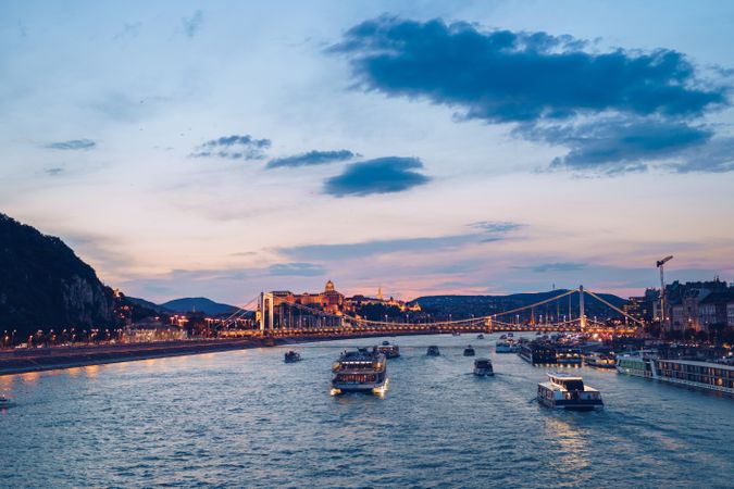 Evening river landscape under cloudy sky with illuminated city