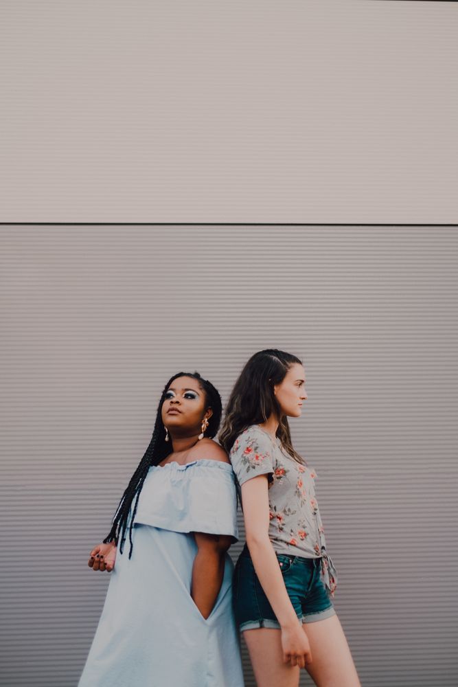 Multiethnic modern women embracing on street wall