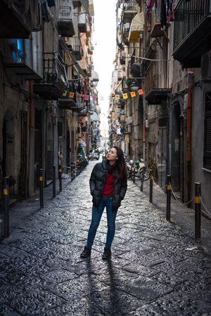 Female traveler in warm wear walking on narrow old street