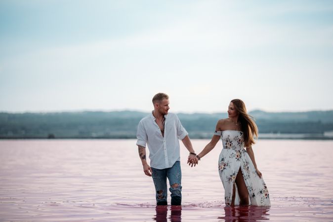 adorable couple walking into an amazing beach with pink water