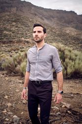 Confident young man standing on stony terrain with savanna grass