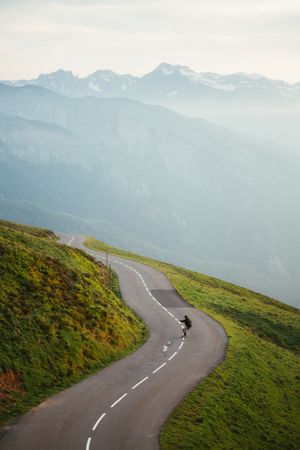 Scenic mountains view and man skateboarding on road